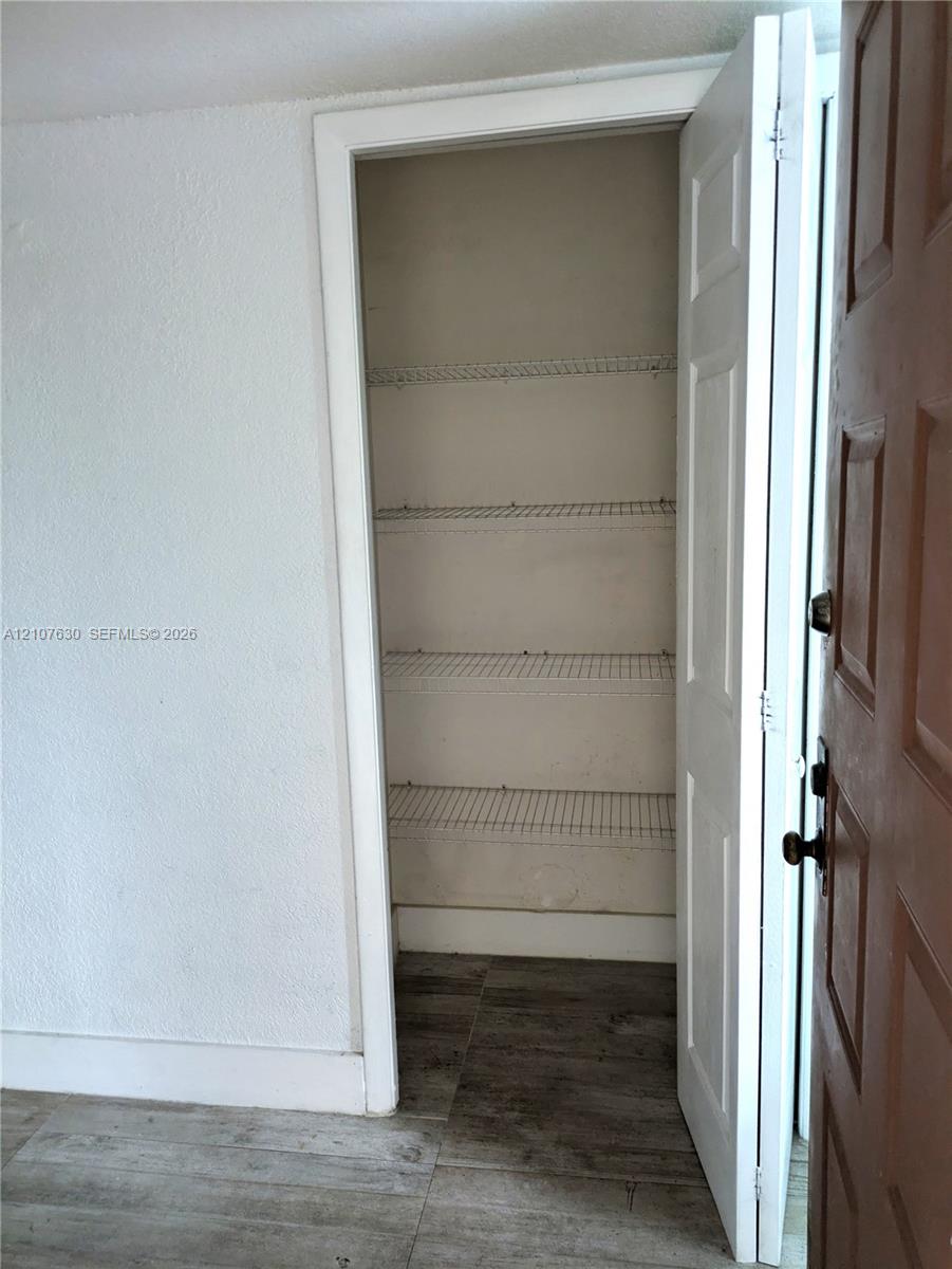 Storage closet featuring white wire shelving and wood-finish flooring