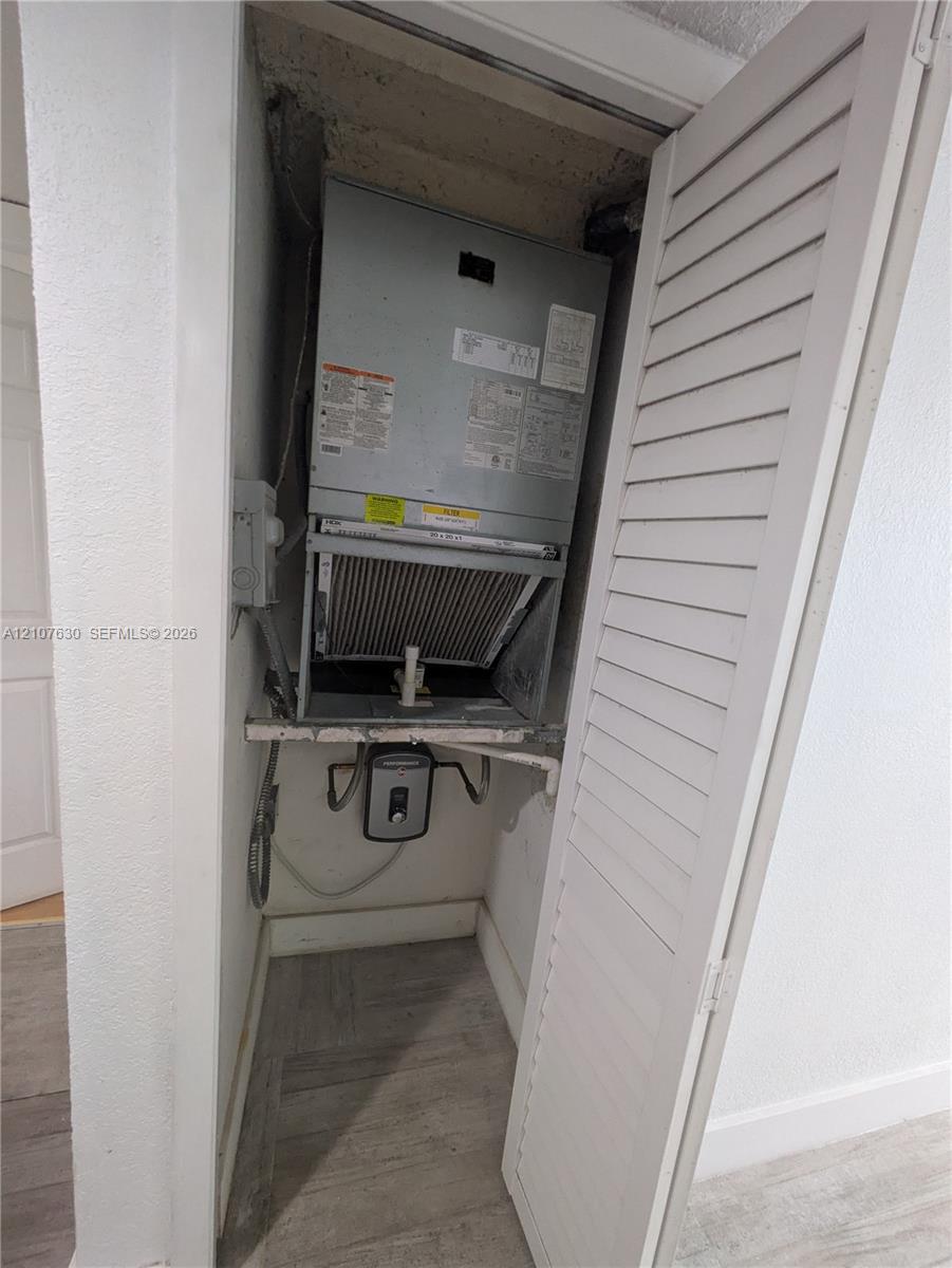 Dedicated mechanical closet housing a forced-air HVAC unit and wall-mounted water heating system, featuring louvered door access