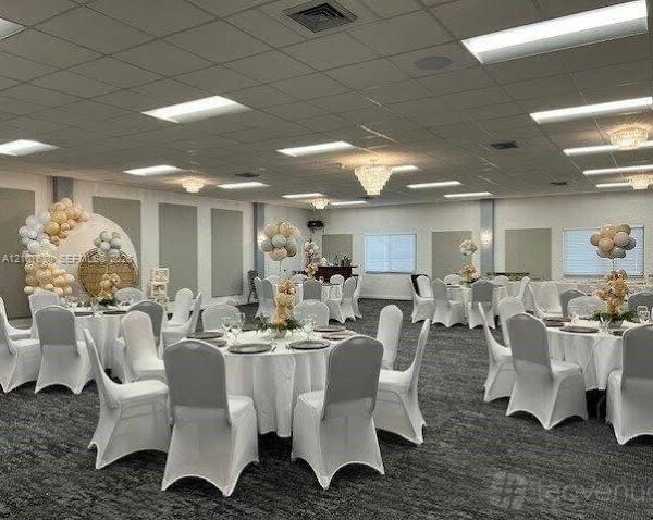 Expansive event hall featuring a drop ceiling with integrated recessed lighting, multiple crystal-style chandeliers, neutral-toned wall panels, and wall-to-wall carpeting