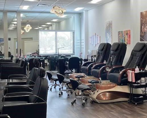Spacious commercial interior featuring wood-finish flooring, recessed ceiling lighting, decorative pendant chandeliers, and expansive floor-to-ceiling mirrors