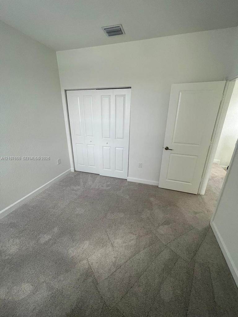 Neutral-toned carpeting, white two-panel interior door, and a built-in sliding closet with white paneled doors