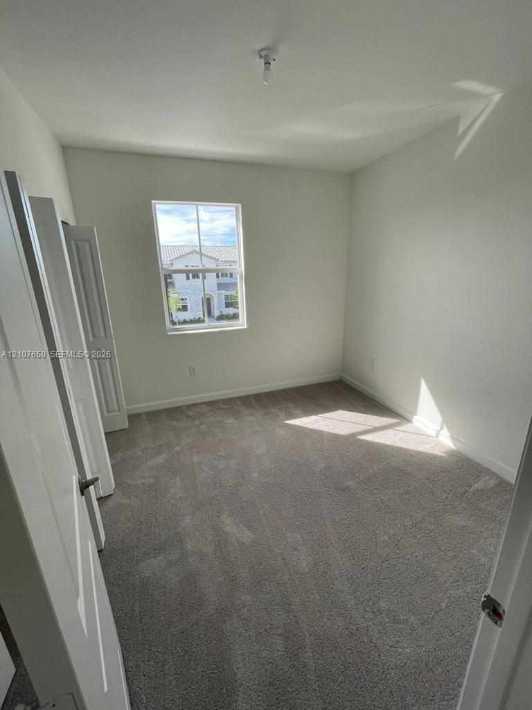 Neutral-toned carpeting, crisp white wall finish, single-hung window with a vertical muntin, and bifold closet doors