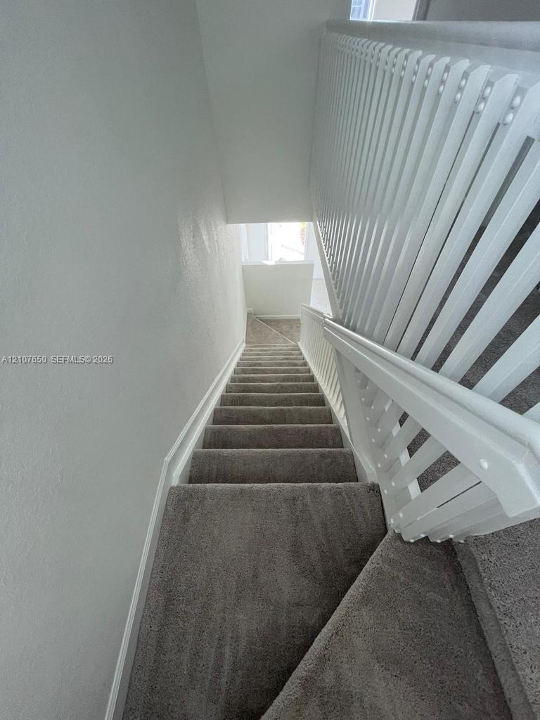 Staircase featuring wall-to-wall carpeting and a white vertical balustrade railing