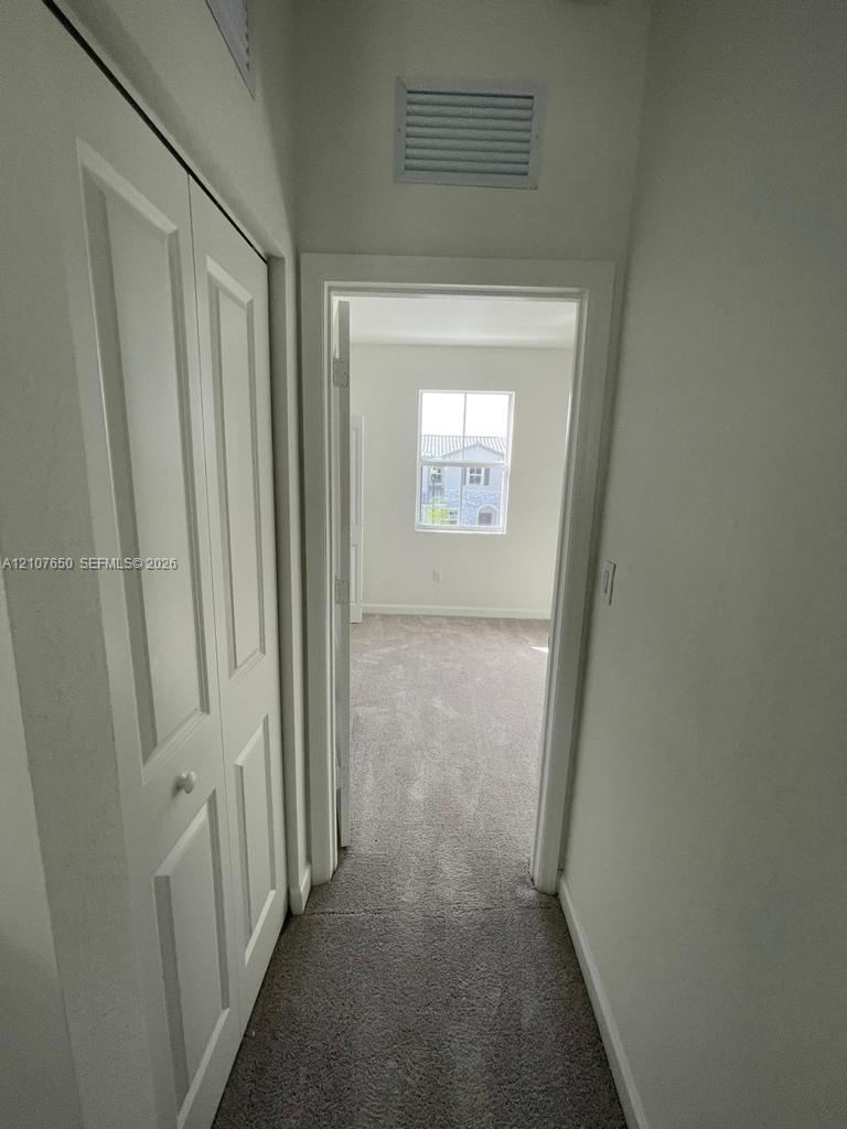 Hallway featuring bi-fold closet doors and neutral carpeting