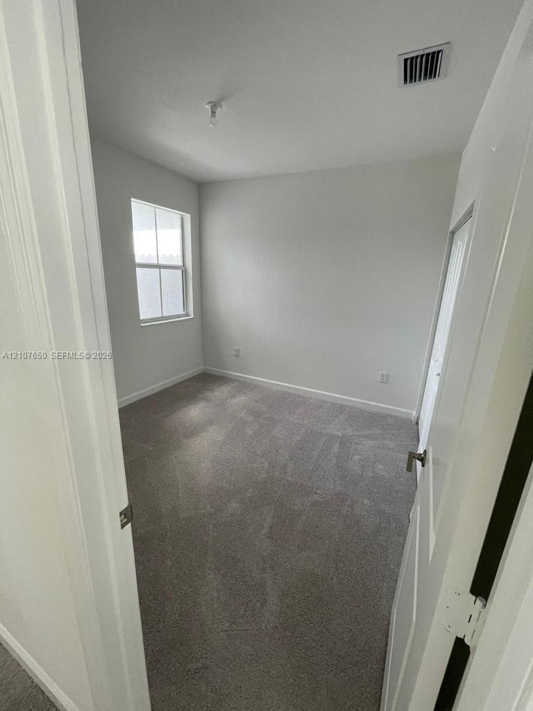 Room featuring neutral-toned carpeting, crisp white walls, and a single-pane window with white trim