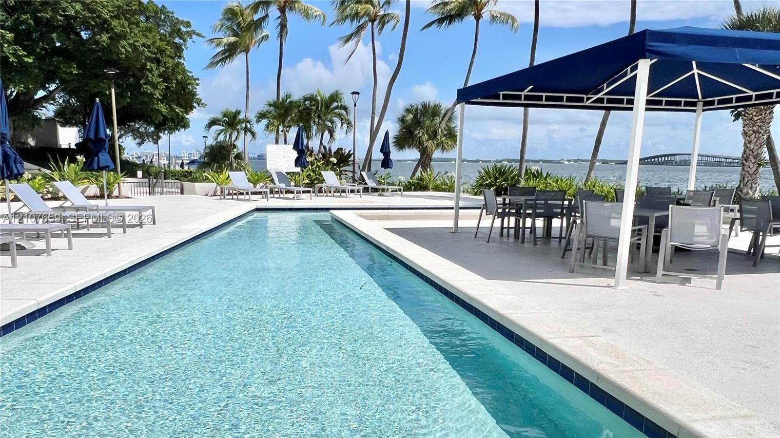 Rectangular lap pool featuring light-toned stone decking and a covered pavilion structure
