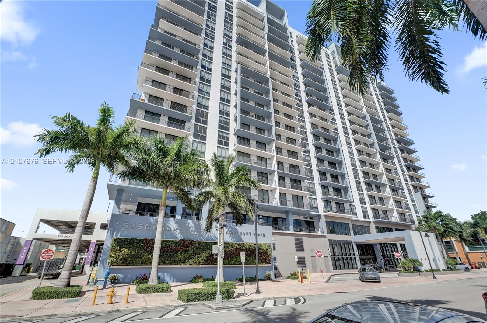 High-rise exterior featuring private balconies, floor-to-ceiling glass paneling, a structured parking facility, and a vertical garden wall