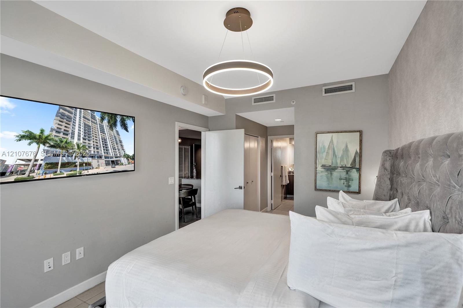 Circular modern LED pendant light fixture, neutral wall color palette, and light-colored tile flooring