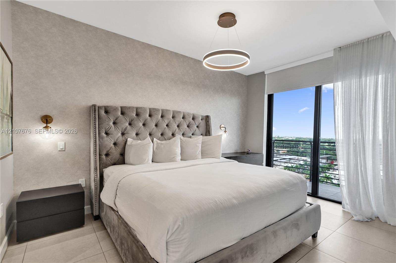 Textured feature wall, modern circular LED pendant lighting, wall-mounted globe sconces, large-format tile flooring, and floor-to-ceiling glass doors opening to a balcony