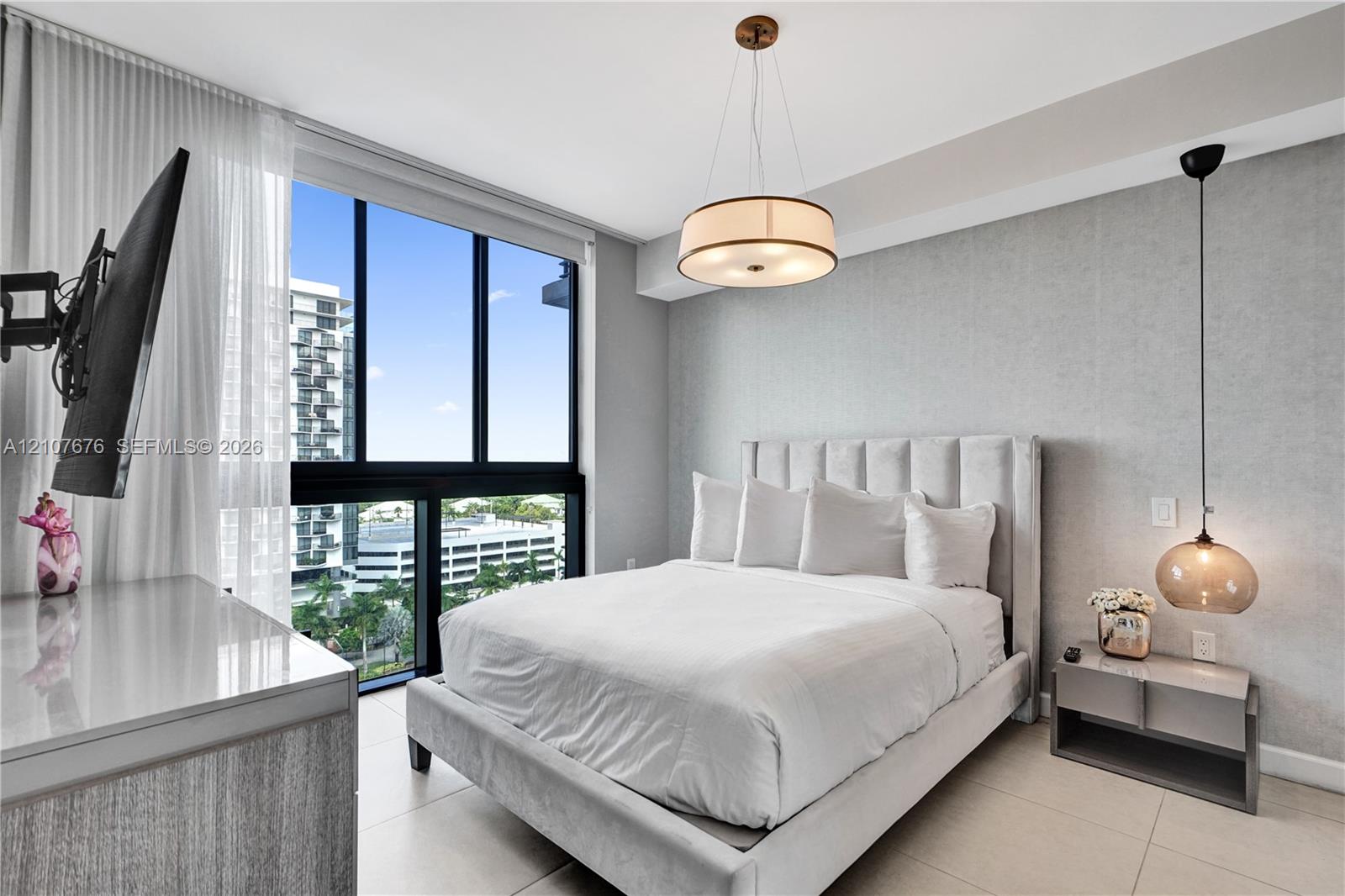 Floor-to-ceiling windows, neutral tile flooring, drum-style chandelier, pendant lighting, and textured wall finish