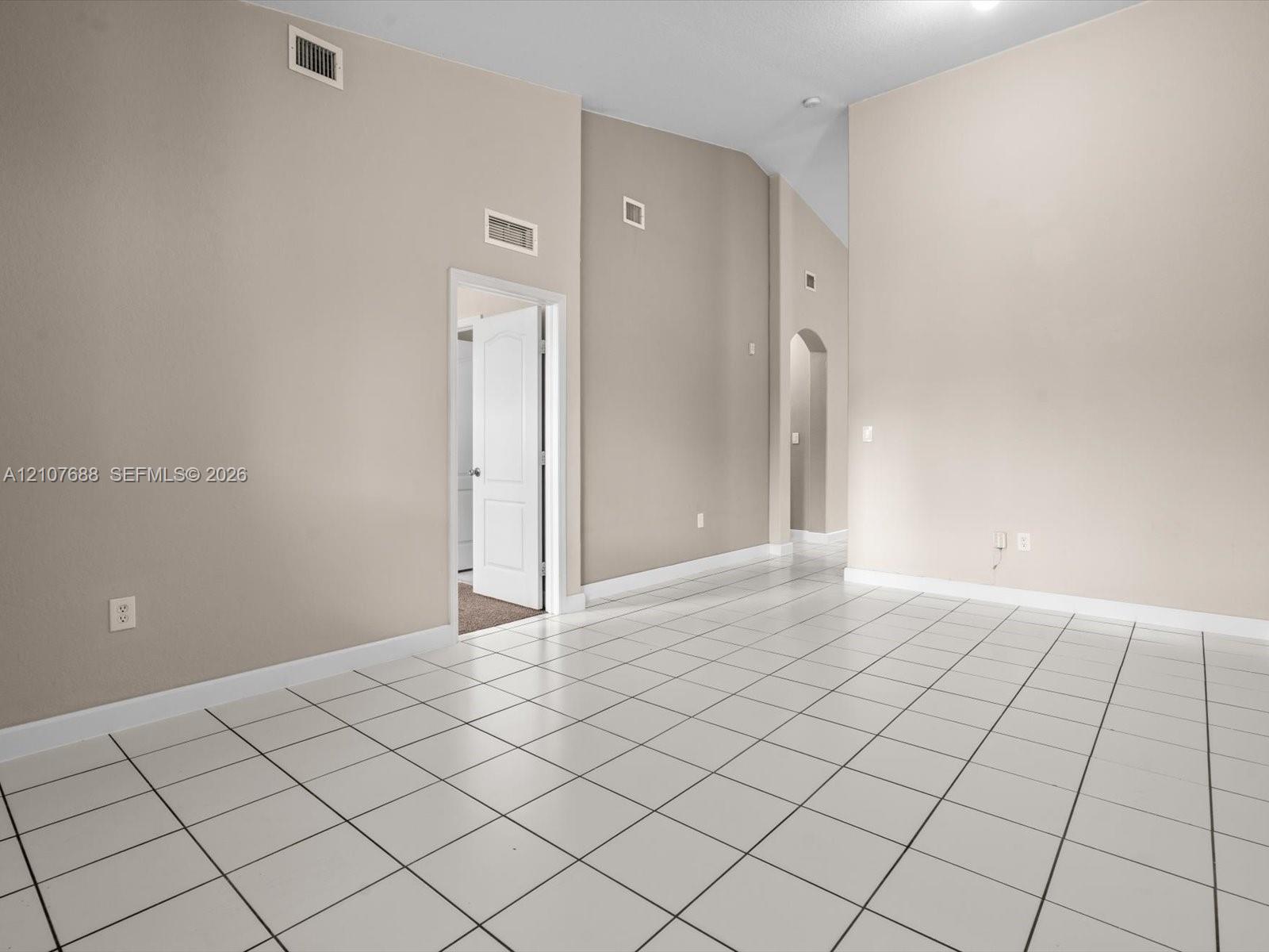 Vaulted ceilings, neutral wall tones, ceramic tile flooring, and an arched entryway
