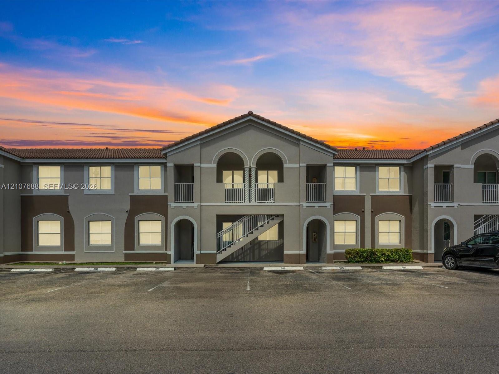 Two-story exterior featuring a clay tile roof, arched entryway details, exterior staircases, and second-level balconies