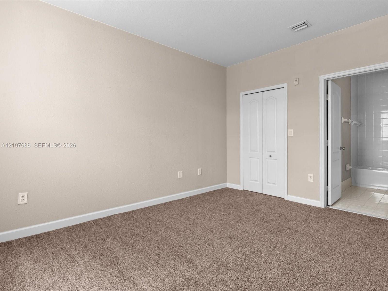 Room featuring neutral wall tones, carpeted flooring, and a white bi-fold closet door