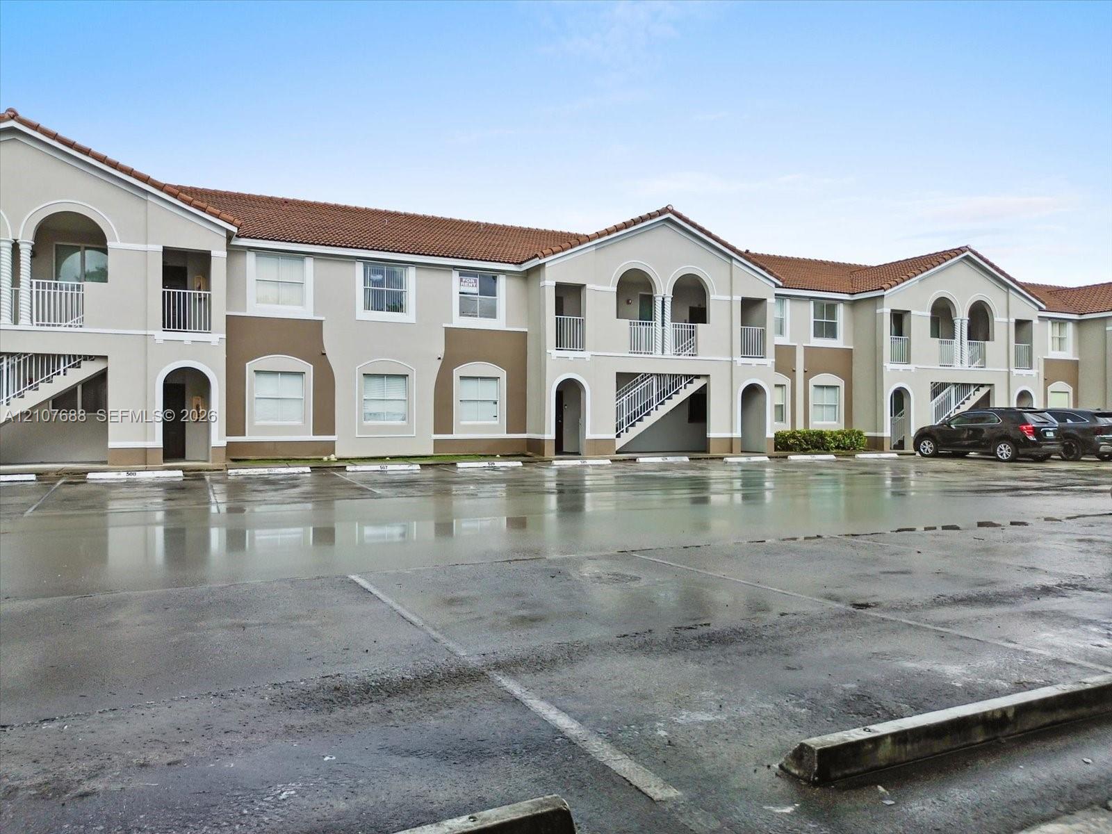 Multi-story exterior featuring a tile roof, stucco facade, arched architectural details, and private balconies with metal railings
