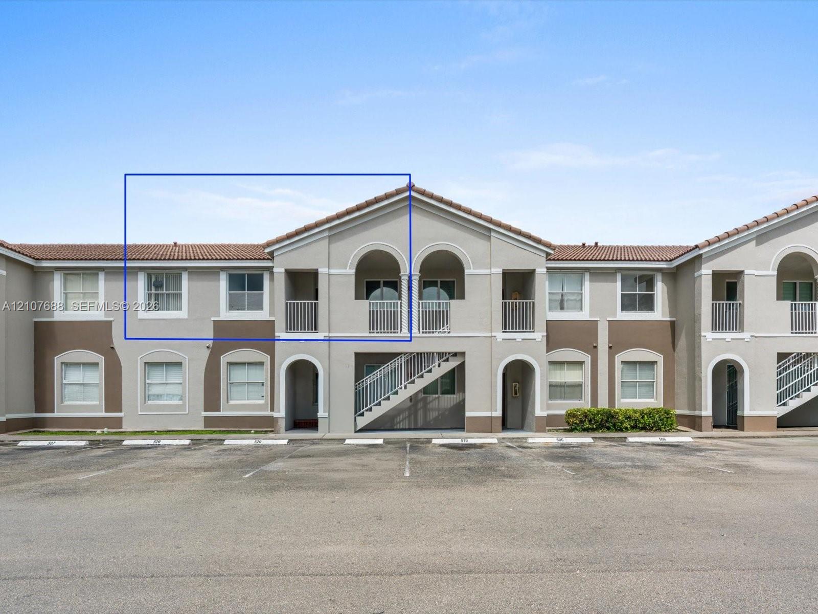 Stucco exterior featuring arched architectural detailing, tile roof, private balcony, and multi-pane windows