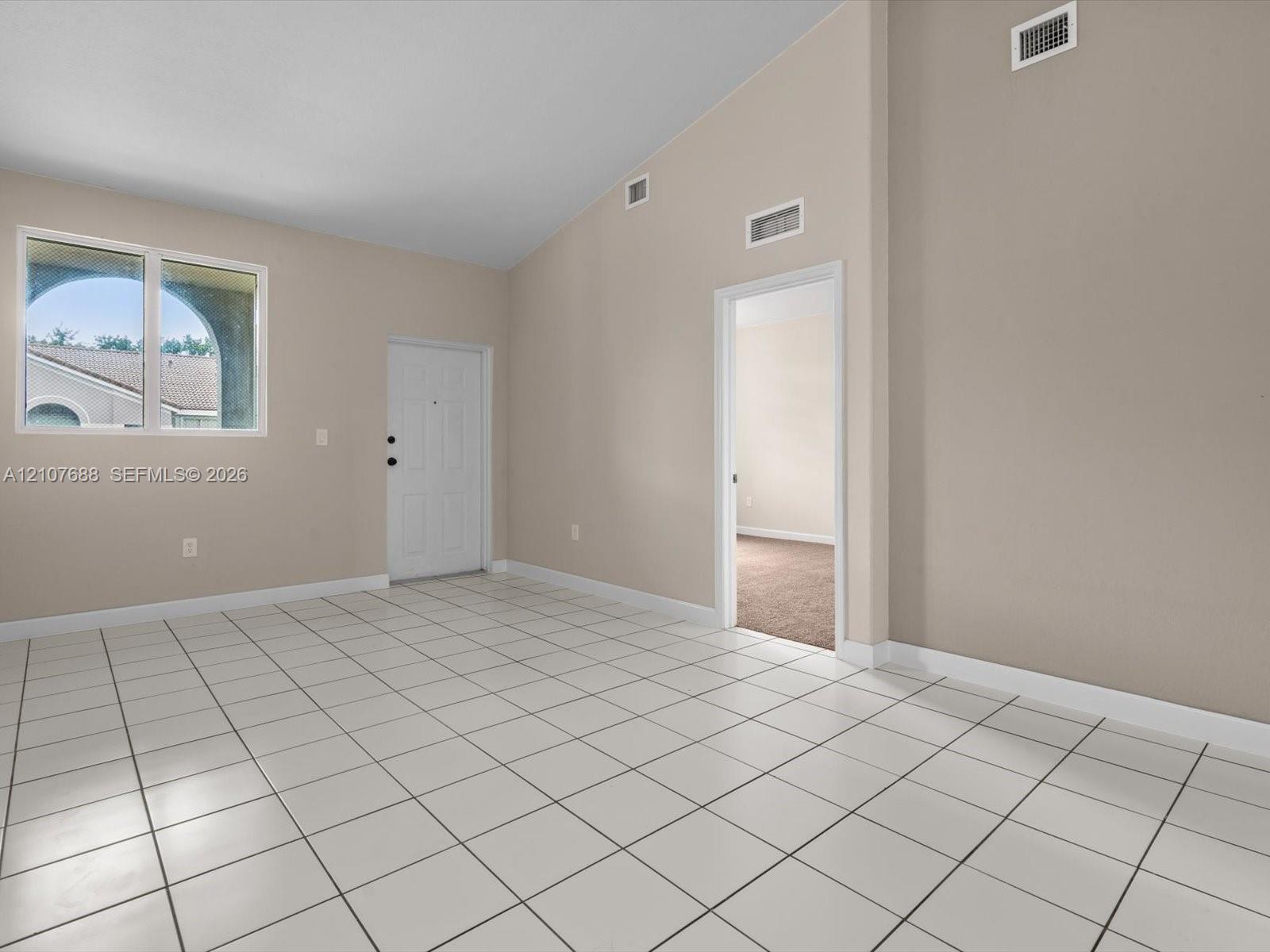 Vaulted ceilings, neutral wall tones, ceramic tile flooring, and oversized windows