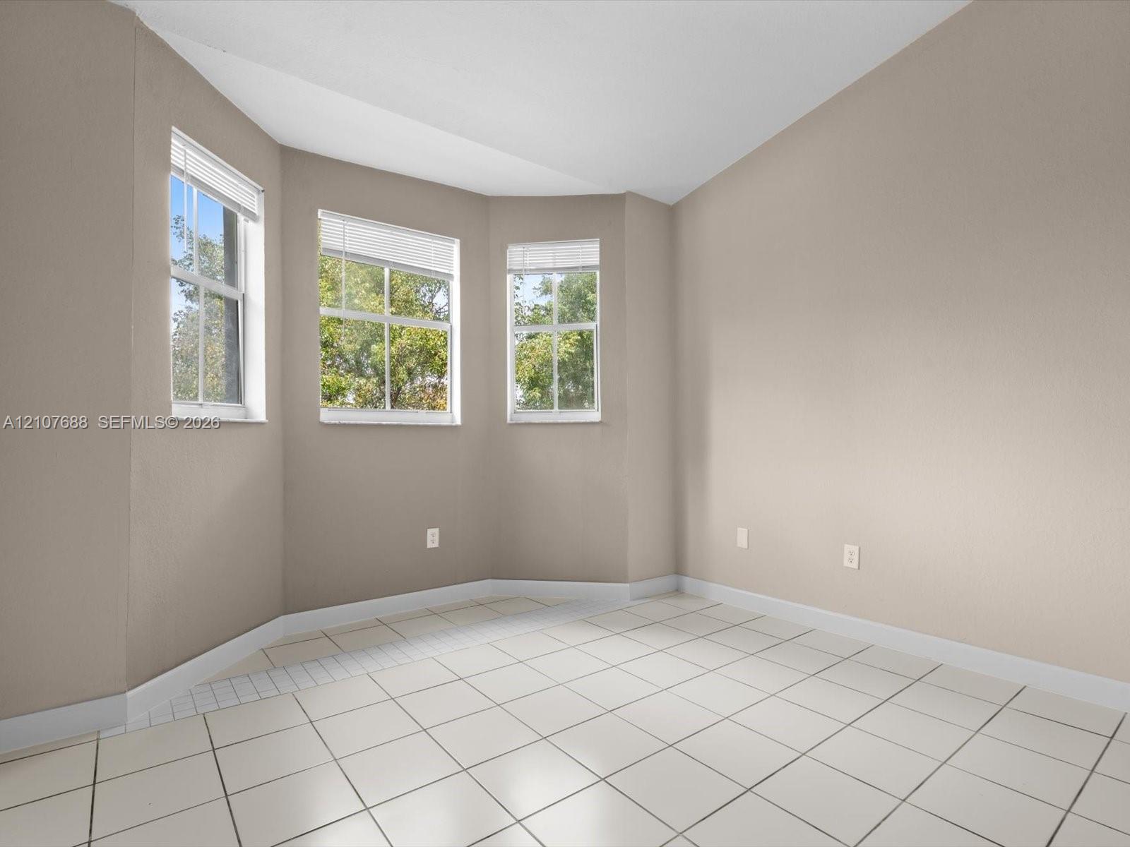 Bay window featuring three paneled windows, neutral wall paint, and ceramic tile flooring