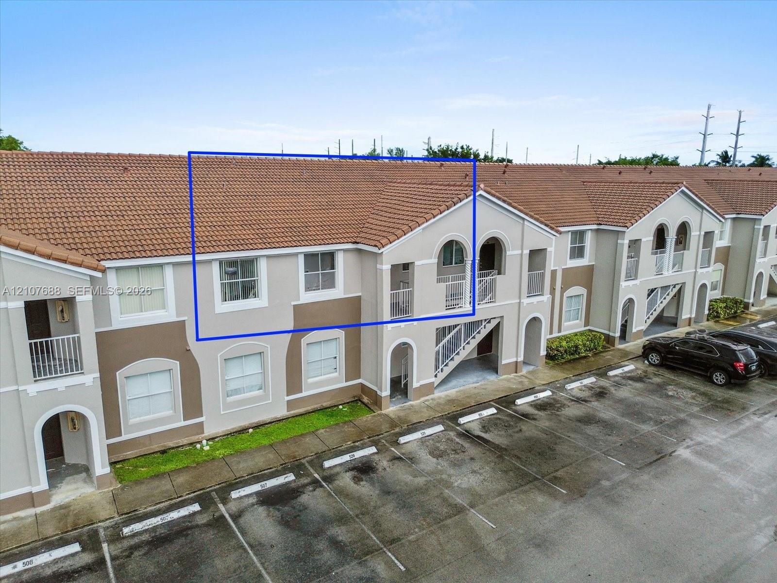 Exterior elevation featuring terracotta-style roof tiles, light-toned stucco facade, arched window detailing, and balcony access