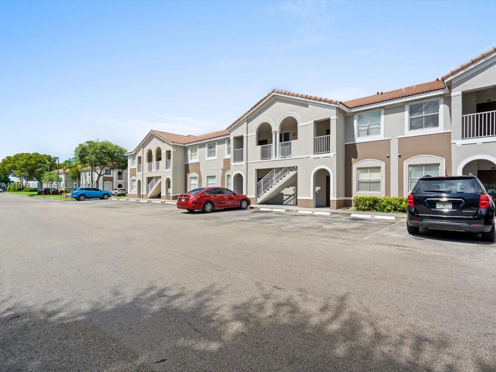 Multi-story exterior featuring a stucco facade, arched architectural detailing, tile roofing, and private balconies with metal railings