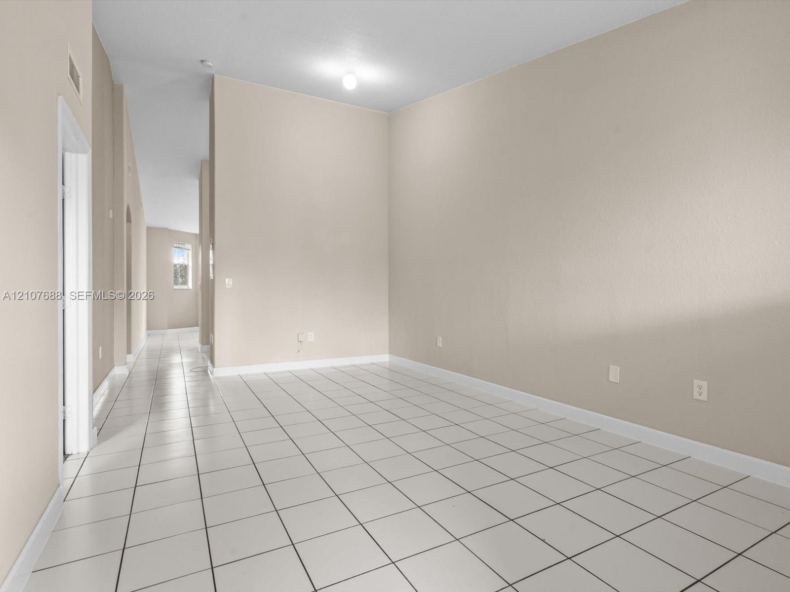 Neutral-toned interior featuring high ceilings, white ceramic tile flooring, and a flush-mount ceiling fixture