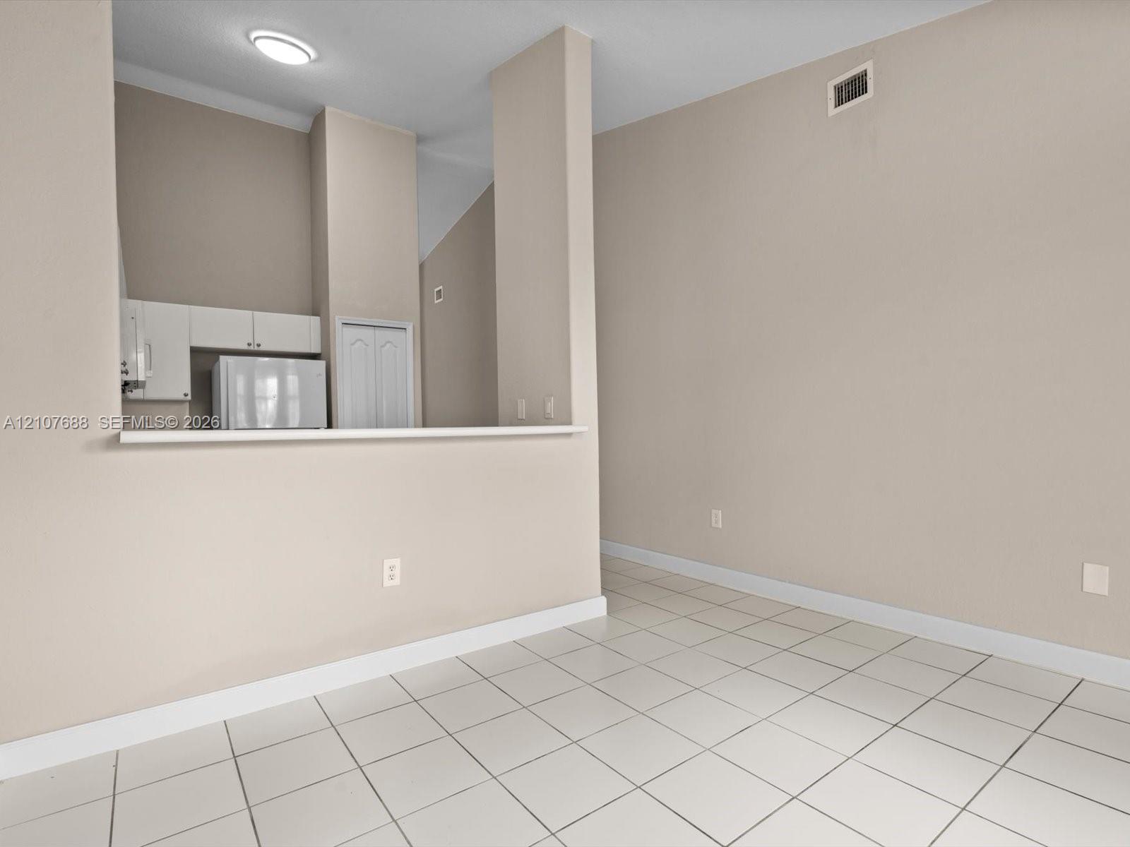 Vaulted ceilings, neutral wall palette, ceramic tile flooring, and a kitchen pass-through counter