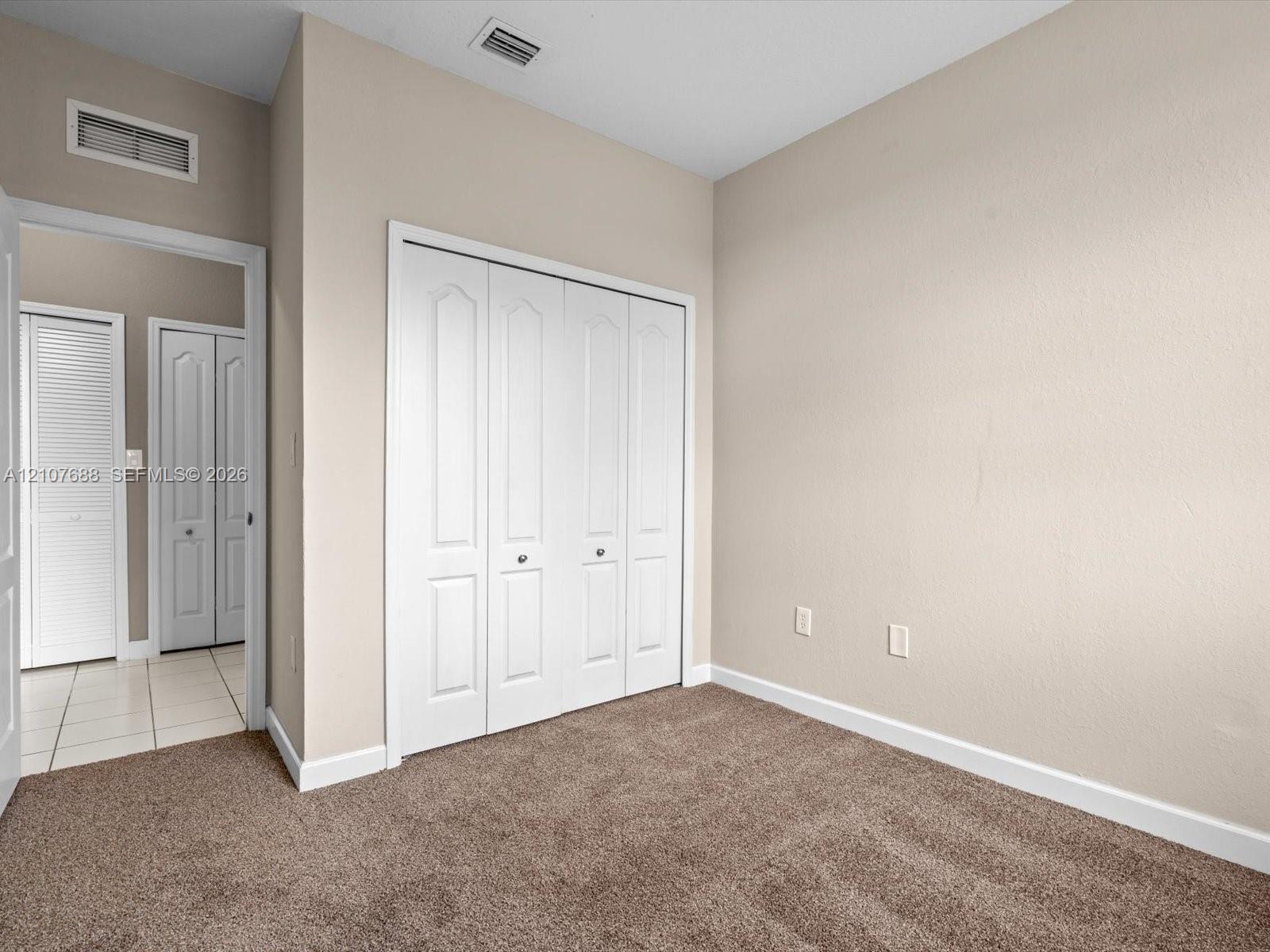 Neutral wall tones, wall-to-wall carpeting, and four-panel bi-fold closet doors