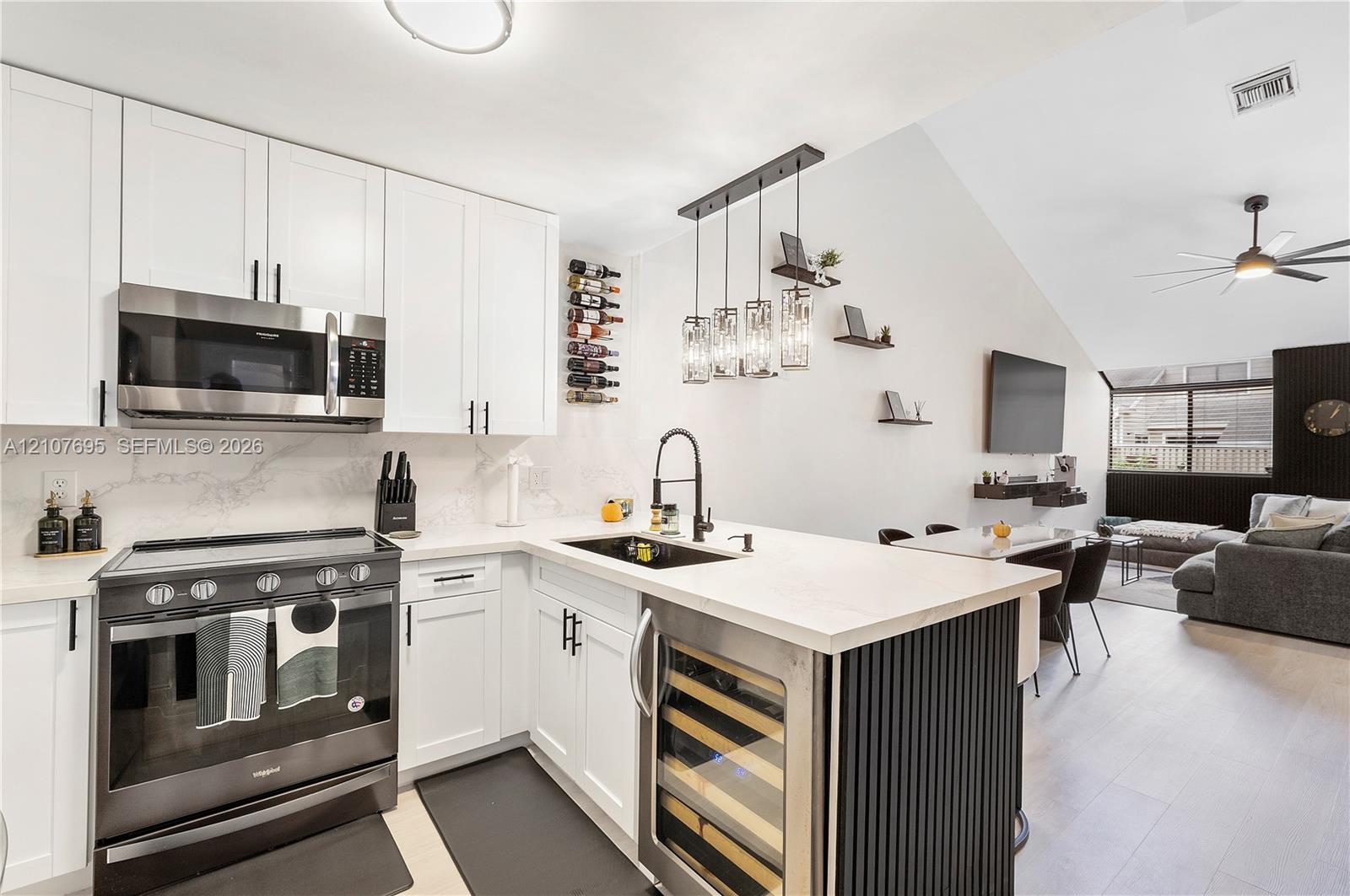 Kitchen featuring white shaker-style cabinetry, quartz countertops with a matching backsplash, stainless steel appliances, a built-in wine refrigerator, and a matte black gooseneck faucet