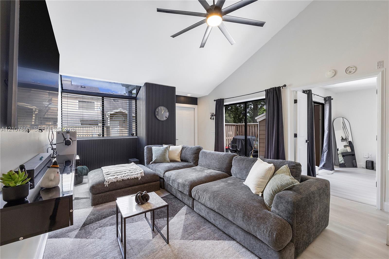Vaulted ceiling featuring a central multi-blade ceiling fan