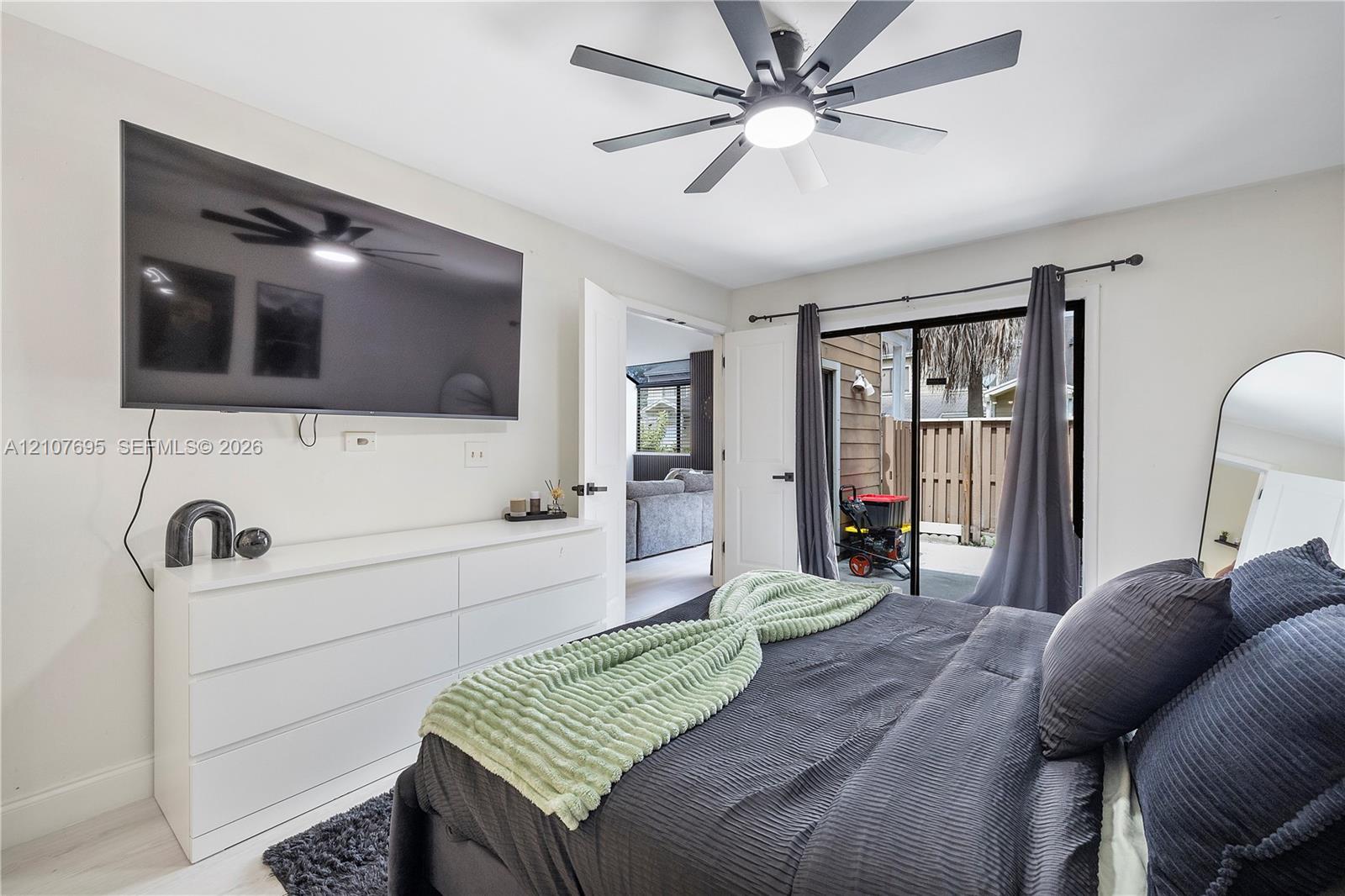 Multi-blade ceiling fan with integrated lighting, sliding glass door with dark metal hardware, and neutral wall tones