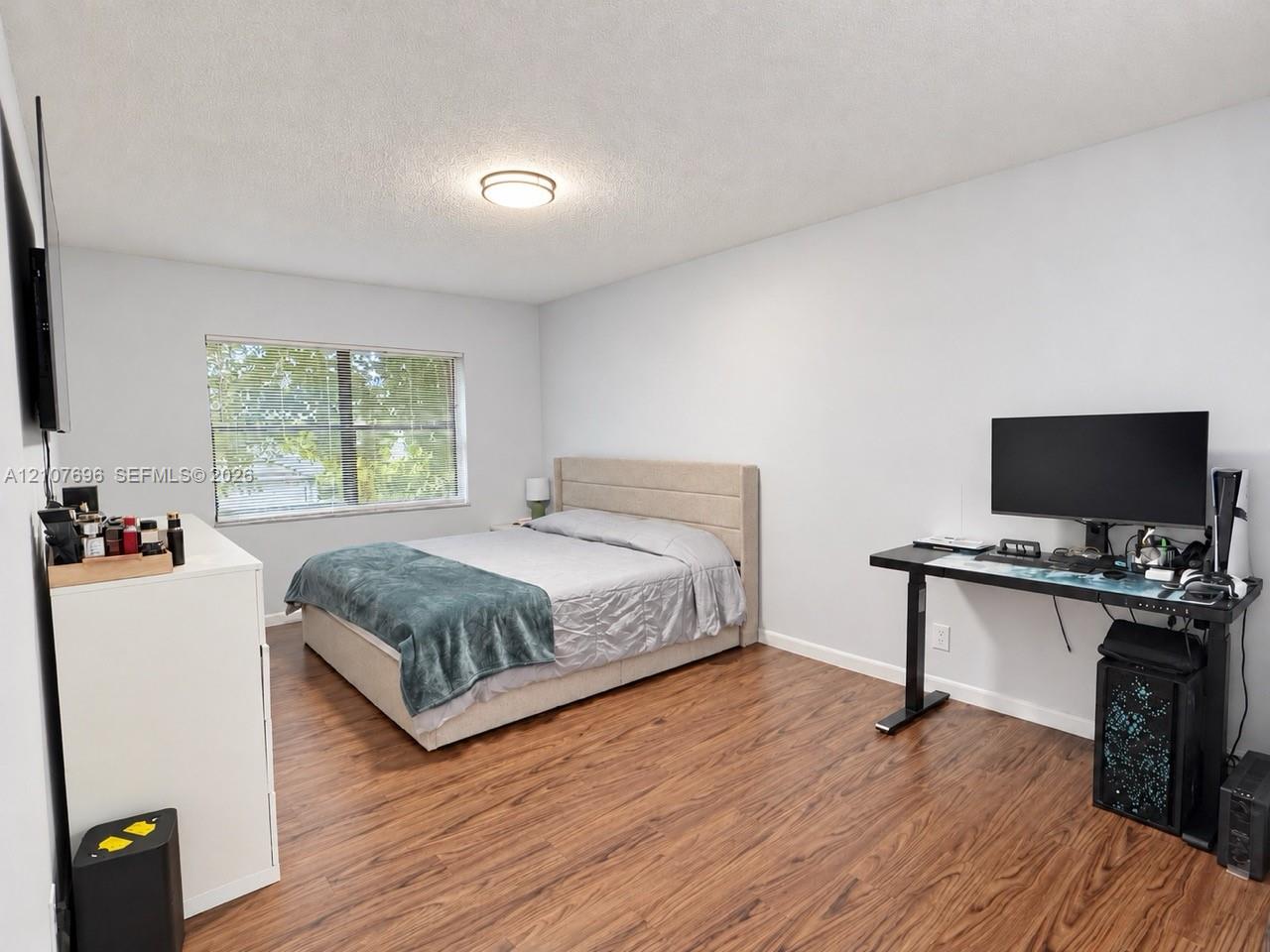 Bedroom featuring wood-finish flooring, a neutral color palette, and a flush-mount ceiling light fixture