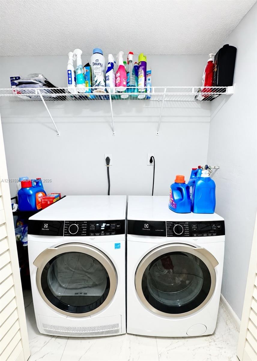 Laundry area featuring white front-load appliances and wall-mounted wire shelving
