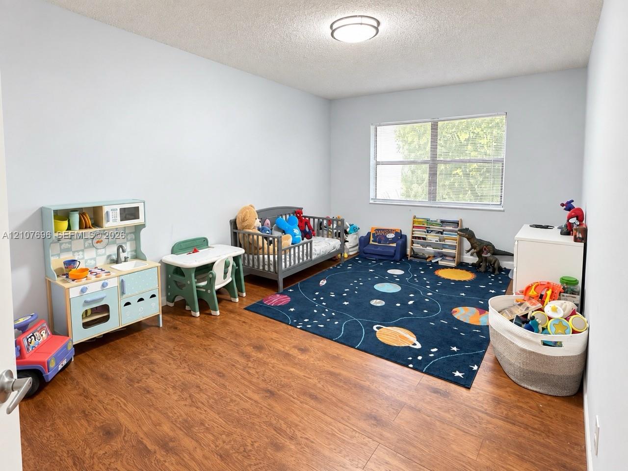 Room featuring wood-finish flooring, a neutral paint palette, and a large window