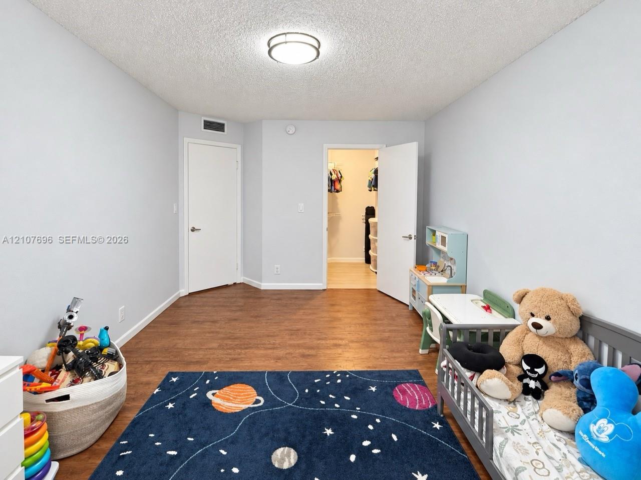 Room featuring wood-finish flooring, a neutral color palette, a flush-mount ceiling light fixture, and an internal storage area with double doors