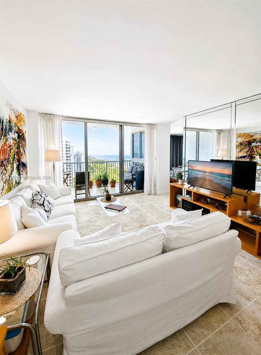 Living area featuring floor-to-ceiling glass sliding doors, stone tile flooring, and a mirrored wall accent
