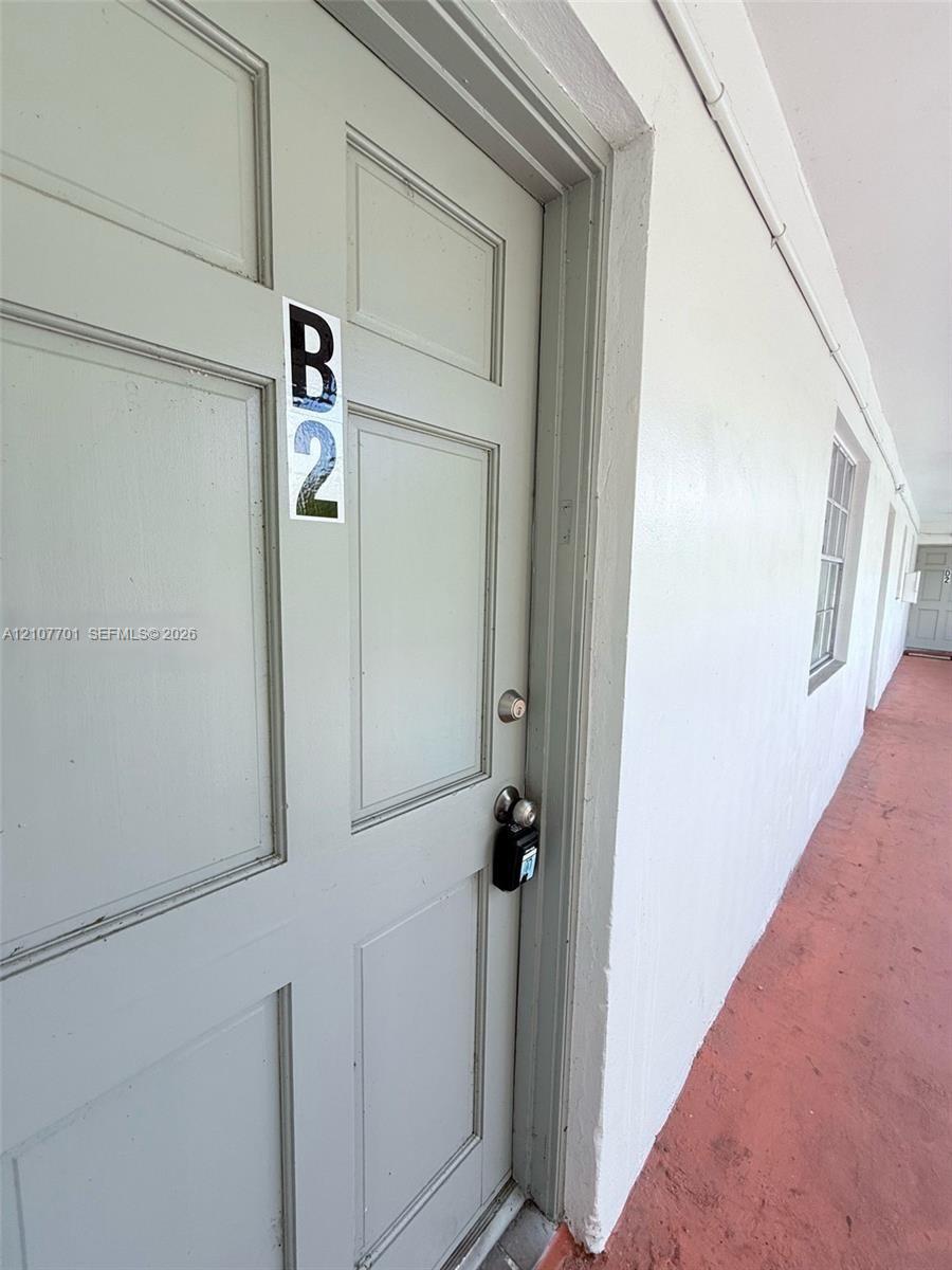 Six-panel exterior door with a satin-finish cylindrical lockset and metallic numerical unit identifier