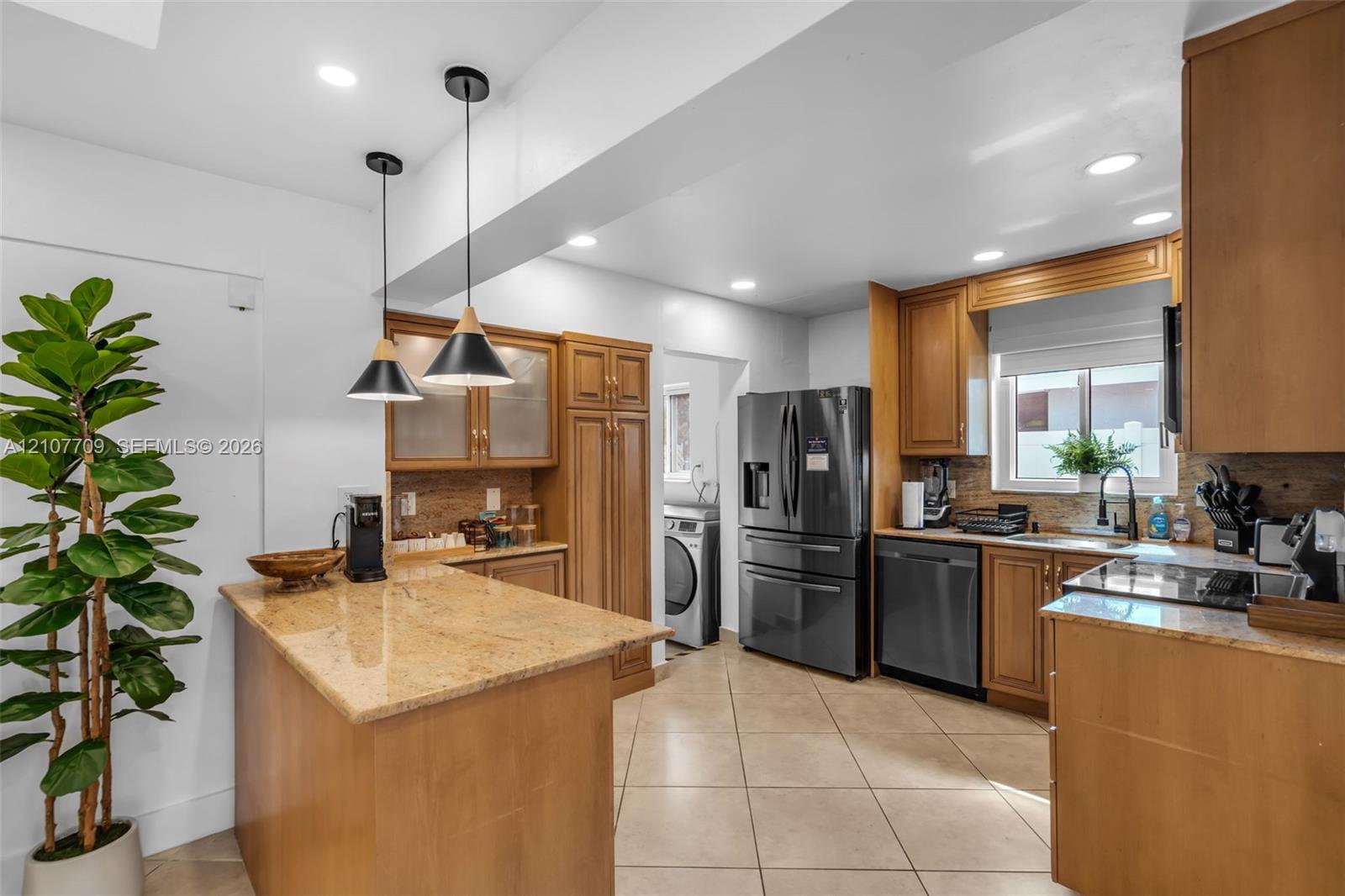 Kitchen featuring stone countertops, natural wood-finish cabinetry, recessed lighting, dual pendant fixtures, and tile flooring