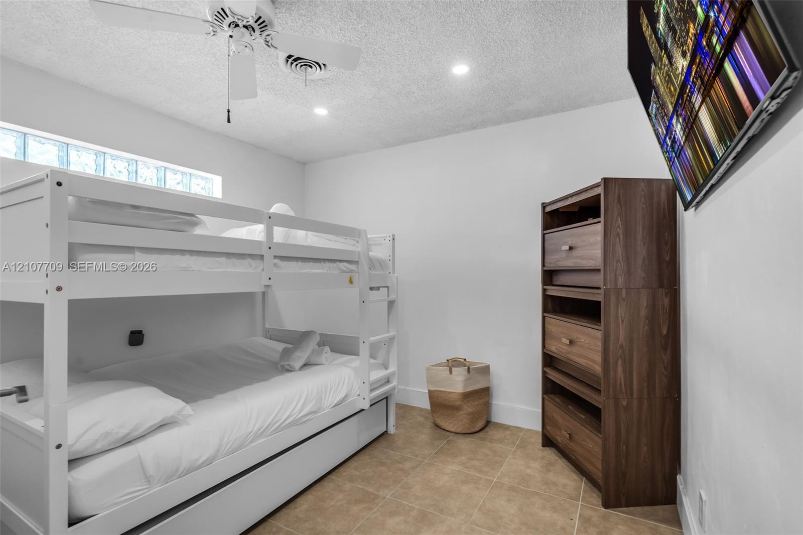 Neutral-toned tile flooring, horizontal glass block window, and ceiling-mounted fan with integrated lighting