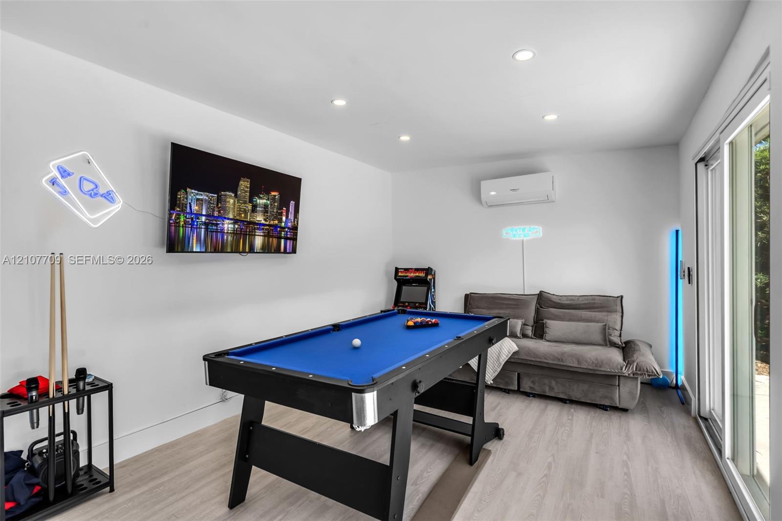 Recessed lighting, wood-finish flooring, and a wall-mounted ductless mini-split HVAC system, with sliding glass doors providing access to the exterior