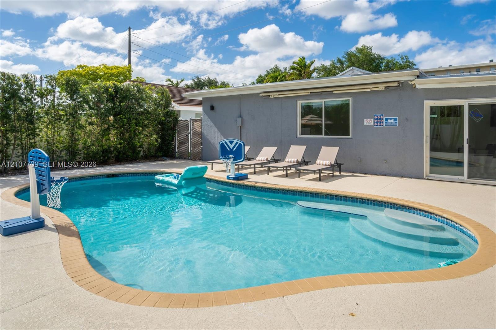 Inground swimming pool with tiled coping, integrated entry steps, and a surrounding concrete pool deck