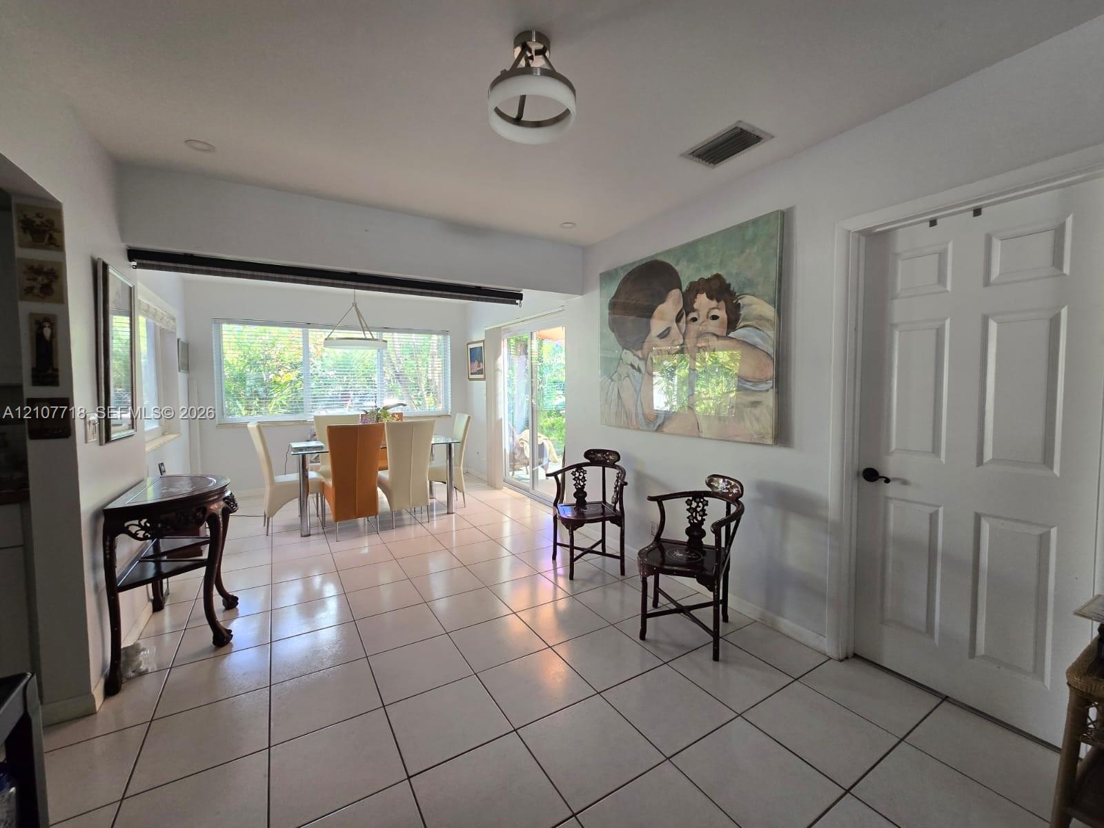 Interior space featuring tile flooring, neutral wall tones, six-panel interior door, multi-pane window, and decorative ceiling light fixture Interior space featuring tile flooring, neutral wall tones, six-panel interior door, multi-pane window, and decorative ceiling light fixture