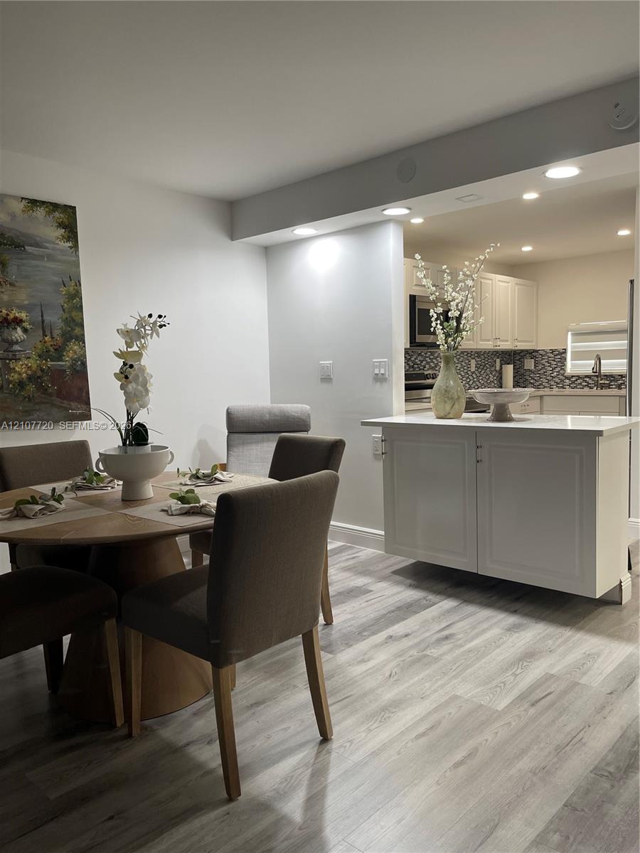 Wood-finish flooring, white cabinetry, quartz-style countertop, and recessed ceiling lighting Wood-finish flooring, white cabinetry, quartz-style countertop, and recessed ceiling lighting