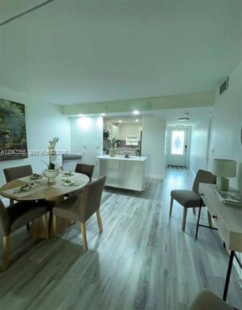 Open-concept interior featuring light wood-finish flooring, a central kitchen island with white cabinetry, and recessed lighting