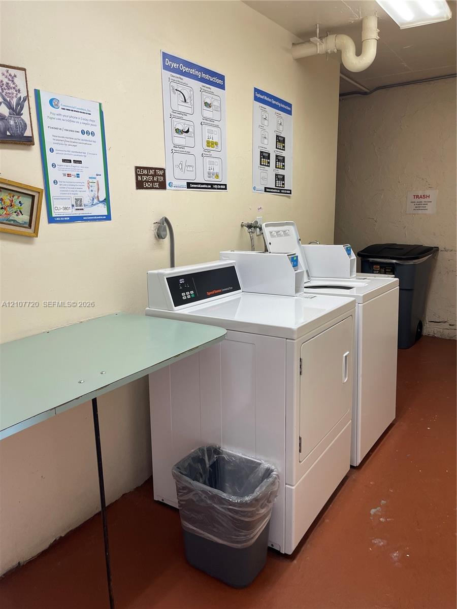 Laundry area featuring high-capacity white top-load washer and front-load dryer units with a built-in folding counter