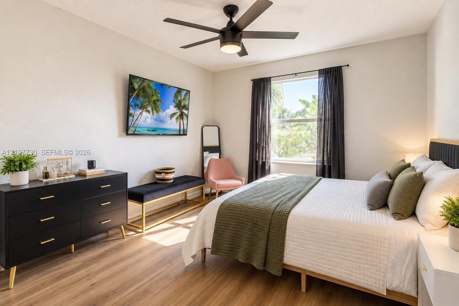Room featuring wood-finish flooring, a matte black multi-blade ceiling fan with integrated lighting, and a single-pane window
