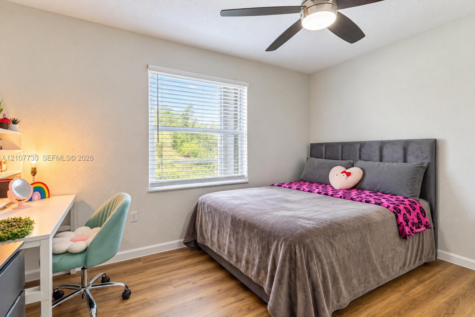 Room featuring wood-finish flooring, a neutral color palette, a large window with horizontal blinds, and a contemporary ceiling fan with integrated lighting