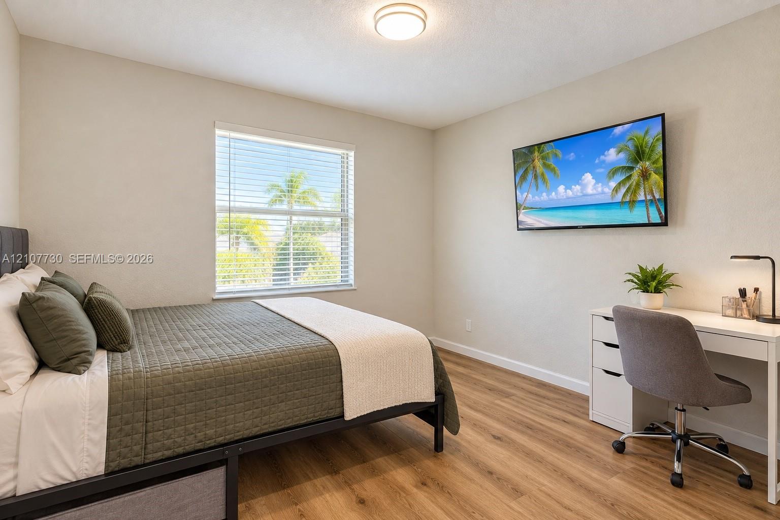 Room featuring wood-finish flooring, a neutral color palette, a single-window configuration with horizontal blinds, and a mounted ceiling light fixture