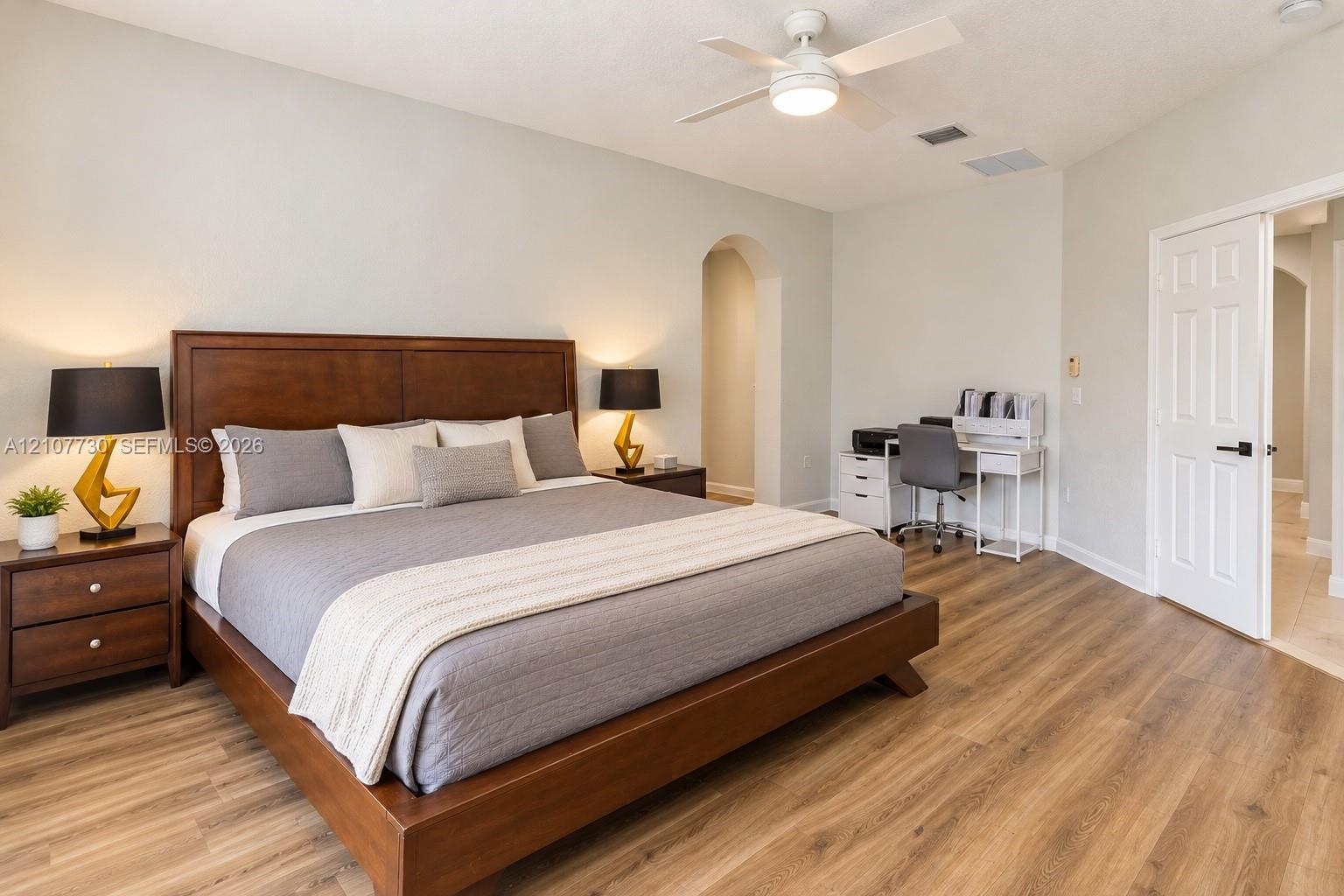 Room featuring wood-finish flooring, vaulted ceiling with a central integrated ceiling fan, and a neutral color palette
