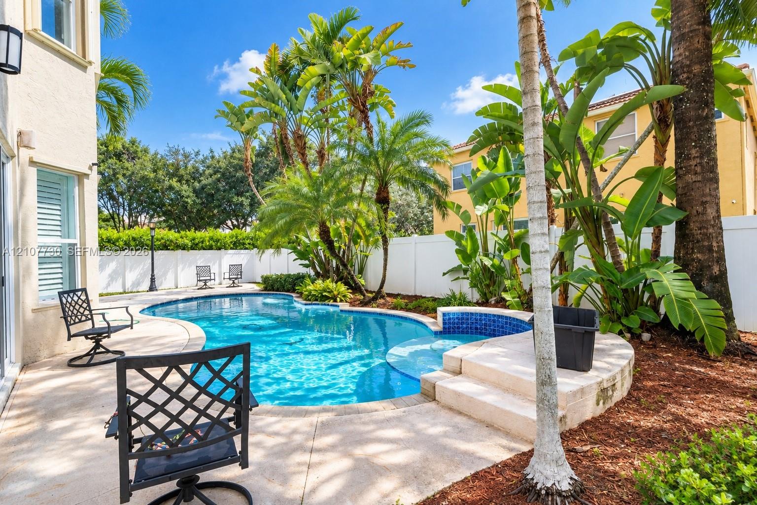 Private outdoor space featuring a swimming pool, integrated spa, concrete patio, and perimeter privacy fencing
