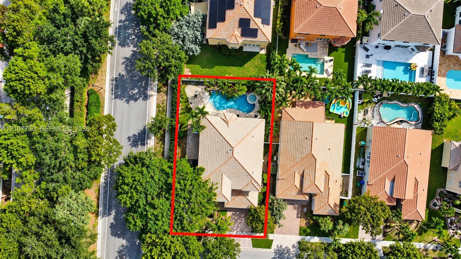 Aerial perspective of a property featuring a tiled roof, an inground swimming pool with a spa, and a paved driveway