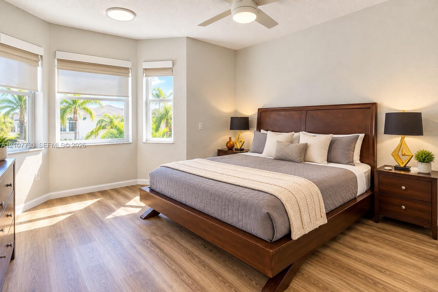 Bay window featuring three large windows, wood-finish flooring, and a white ceiling fan with integrated lighting